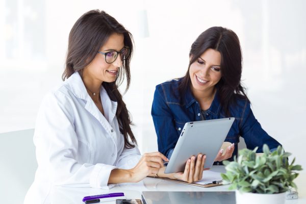 doctor and her patient choosing mammary prosthesis in the office scaled