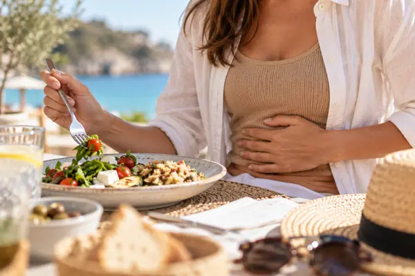 Mujer con molestias digestivas durante una comida en verano